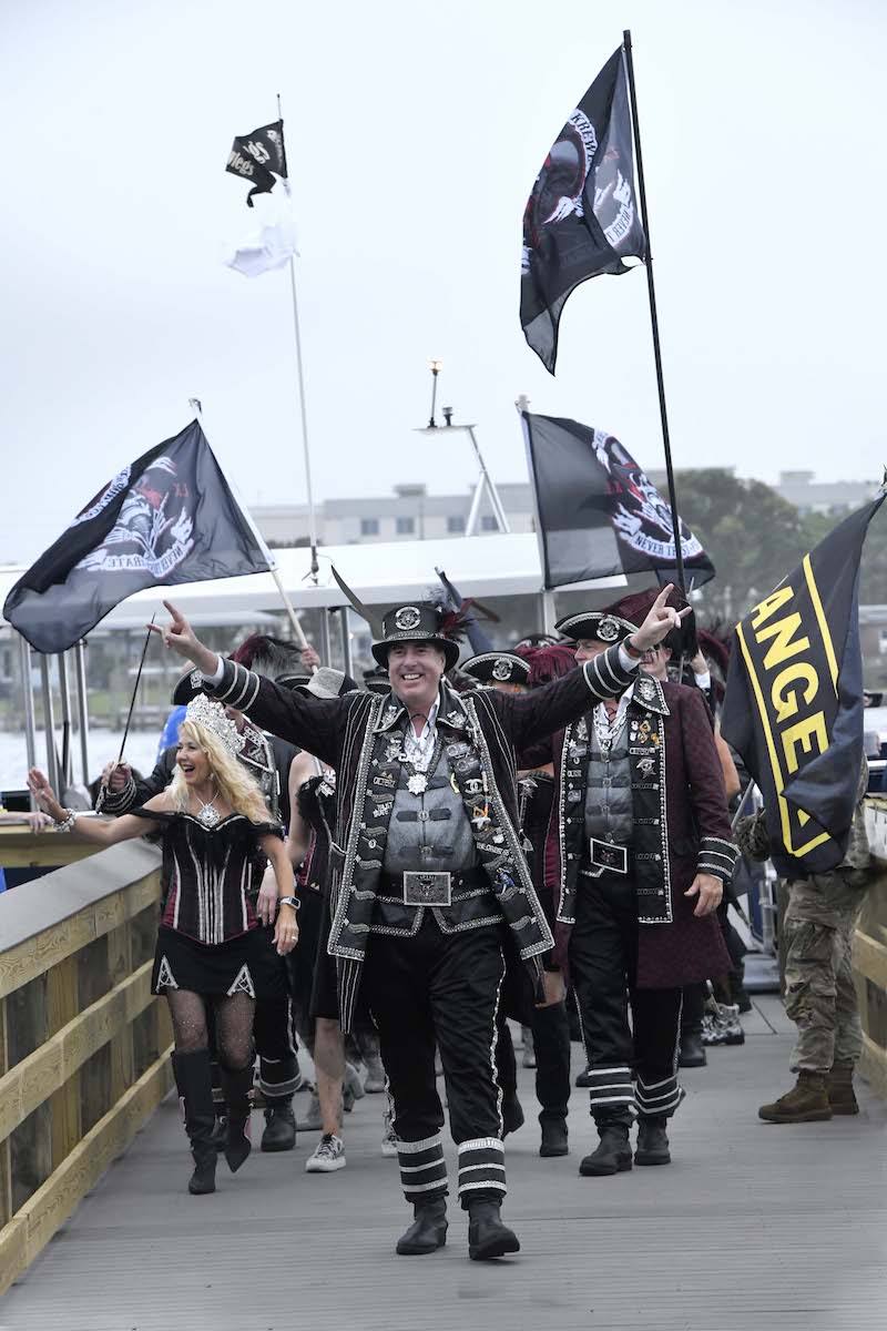 Men and women in pirate costumes walking, waving and carrying flags