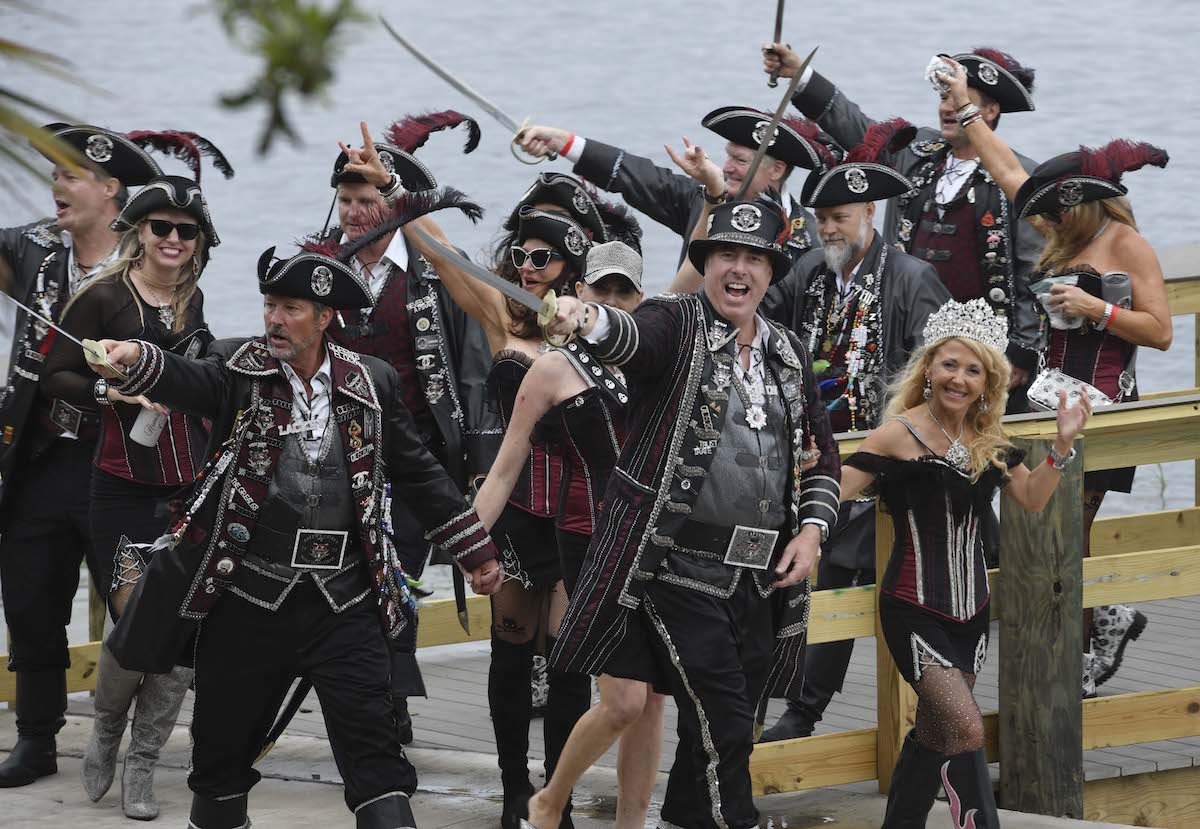 Men and women in pirate costumes walking and waving swords